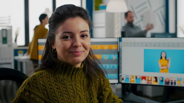 Photo retoucher sitting in creative workplace looking at camera smiling