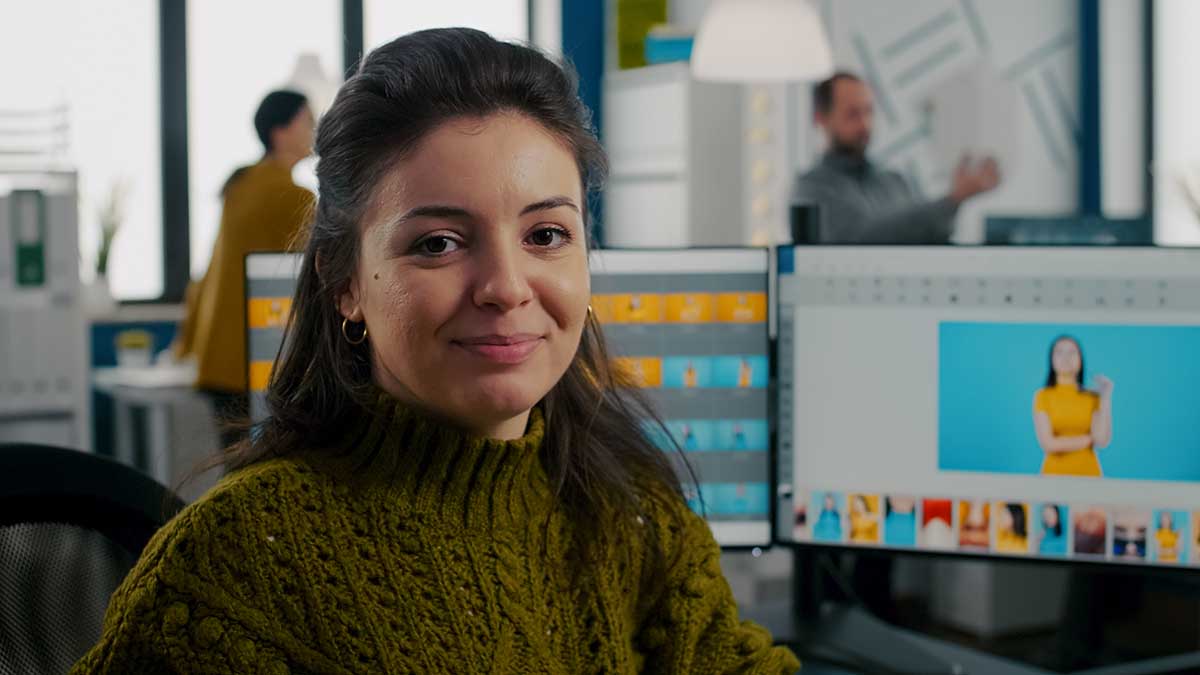 Photo retoucher sitting in creative workplace looking at camera smiling